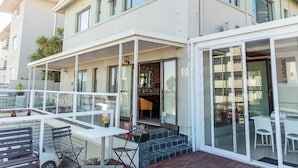A two-story building with a covered outdoor seating area, a visible entrance, and a staircase leading to the entrance. - Leeuwenzee Guest House (Cape Town)