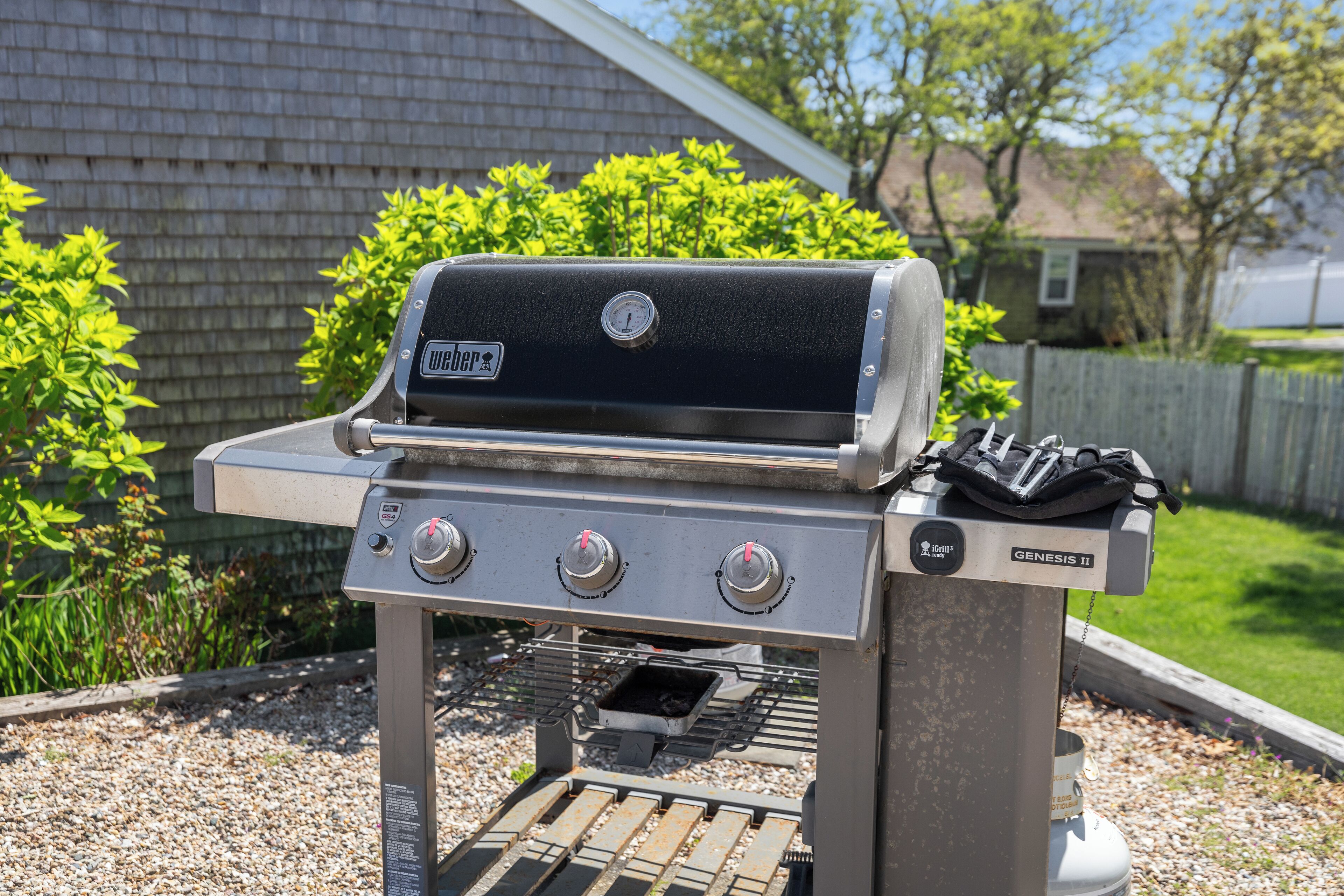 A portable Genesis II grill with a digital display, three control knobs, and a side burner.
