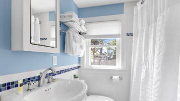 Ein Badezimmer mit einem weißen Waschbecken, einem Spiegel, einer Toilette und einem Fenster mit Ausblick.