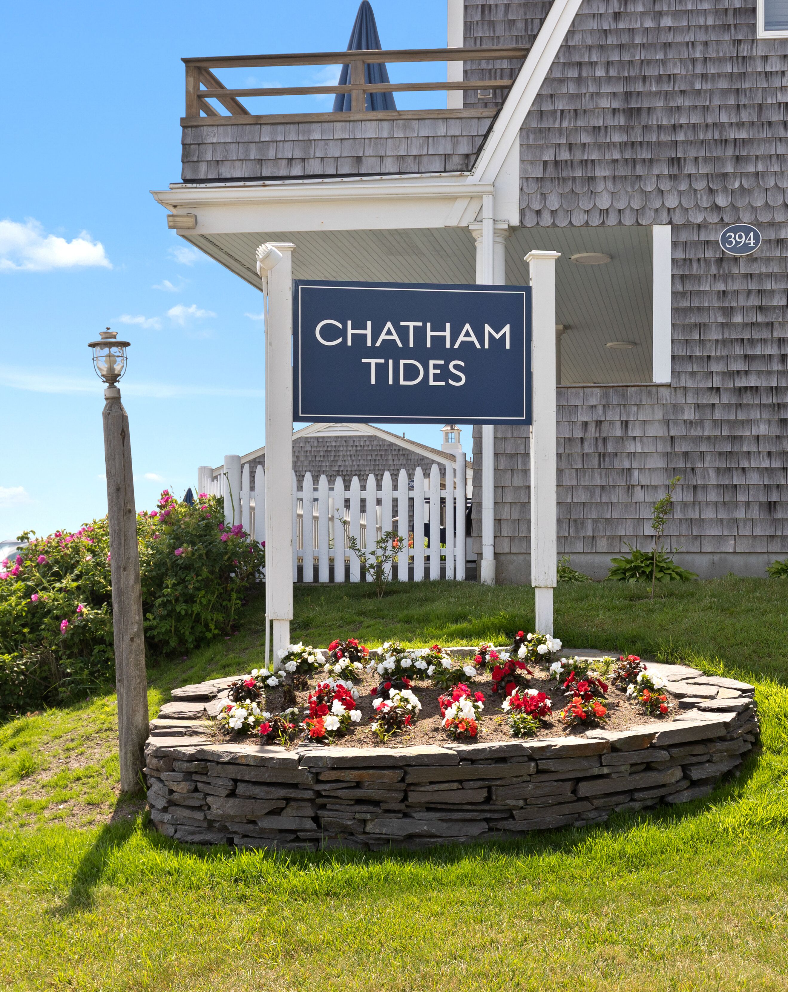 A sign reading "Chatham Tides" with a stone flower bed in front.