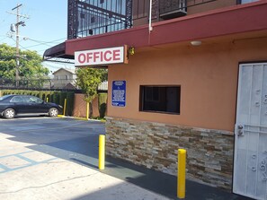 A building with a sign reading "OFFICE" and a parking lot with a car. - Travel Inn Motel (Los Angeles)