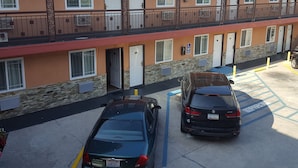 A motel with a two-story structure, multiple rooms, and a parking area with two cars.