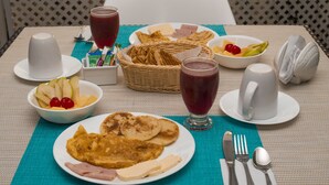 A breakfast setting with plates of food, a basket, and drinks on a table. - San Luis Place By Dorado (San Andrés)