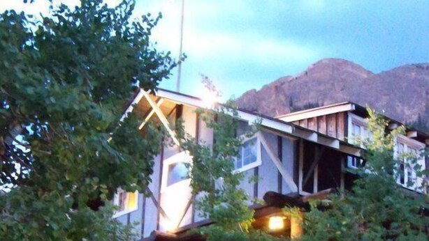 A multi-story building with a wooden deck and a sign that reads "OPEN". - Baldpate Inn (Estes Park)
