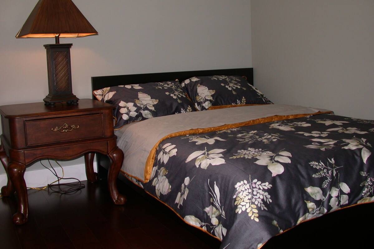 A bedroom with a bed, a nightstand, and a lamp.