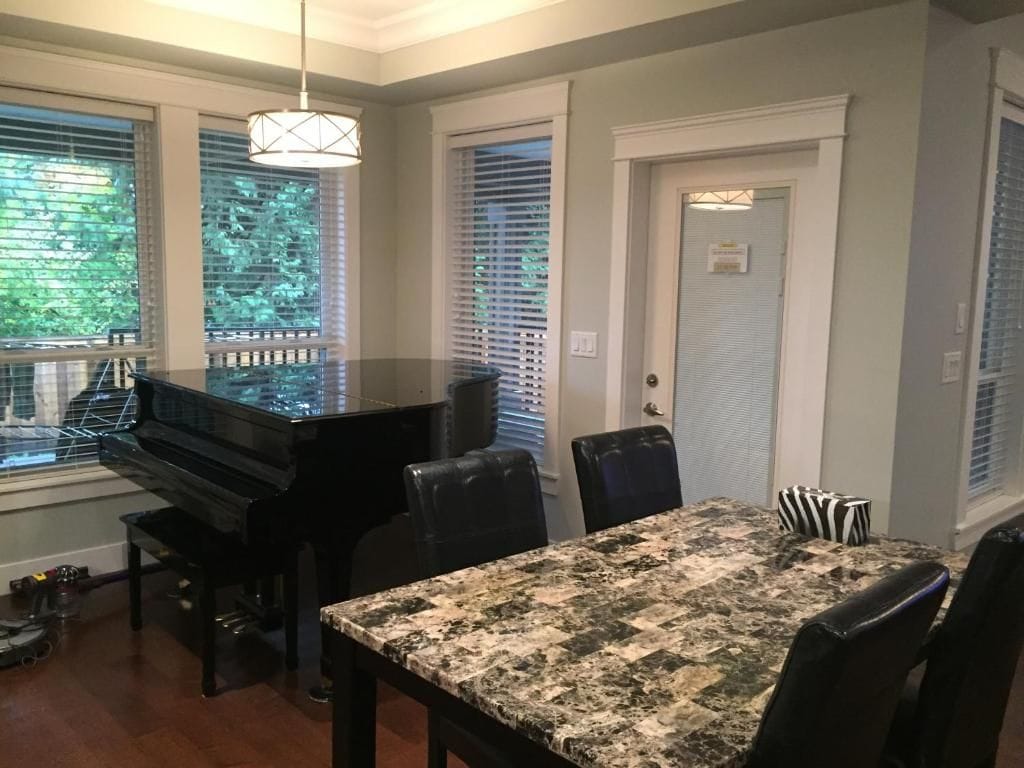 A dining area with a piano, a table with a patterned tablecloth, and chairs.