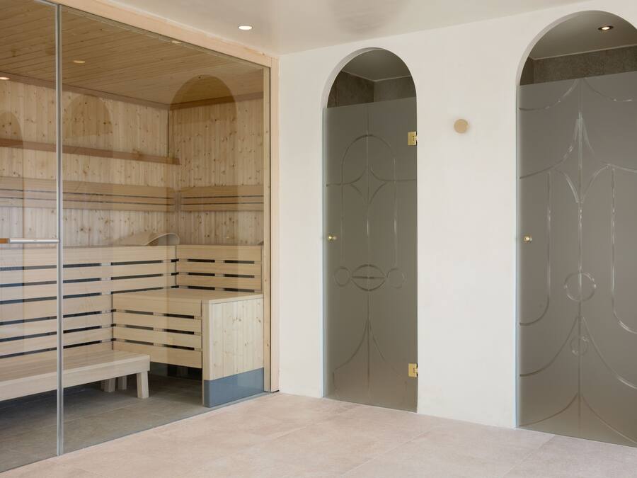 A sauna room with wooden benches and a glass partition.
