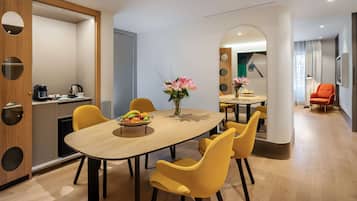 A modern dining area with a wooden table, yellow chairs, and a vase of flowers.
