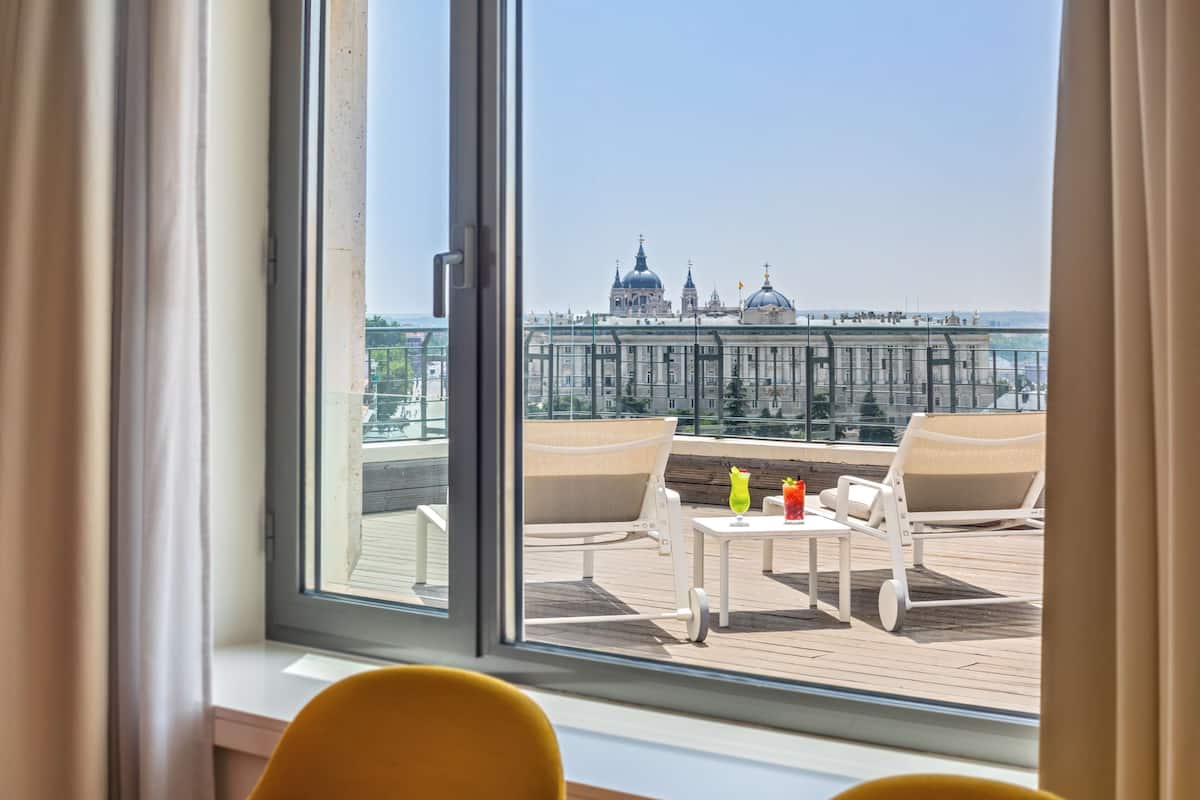 Una habitación con un ventanal grande que da a una vista panorámica de la ciudad, con edificios históricos y una zona costera.
