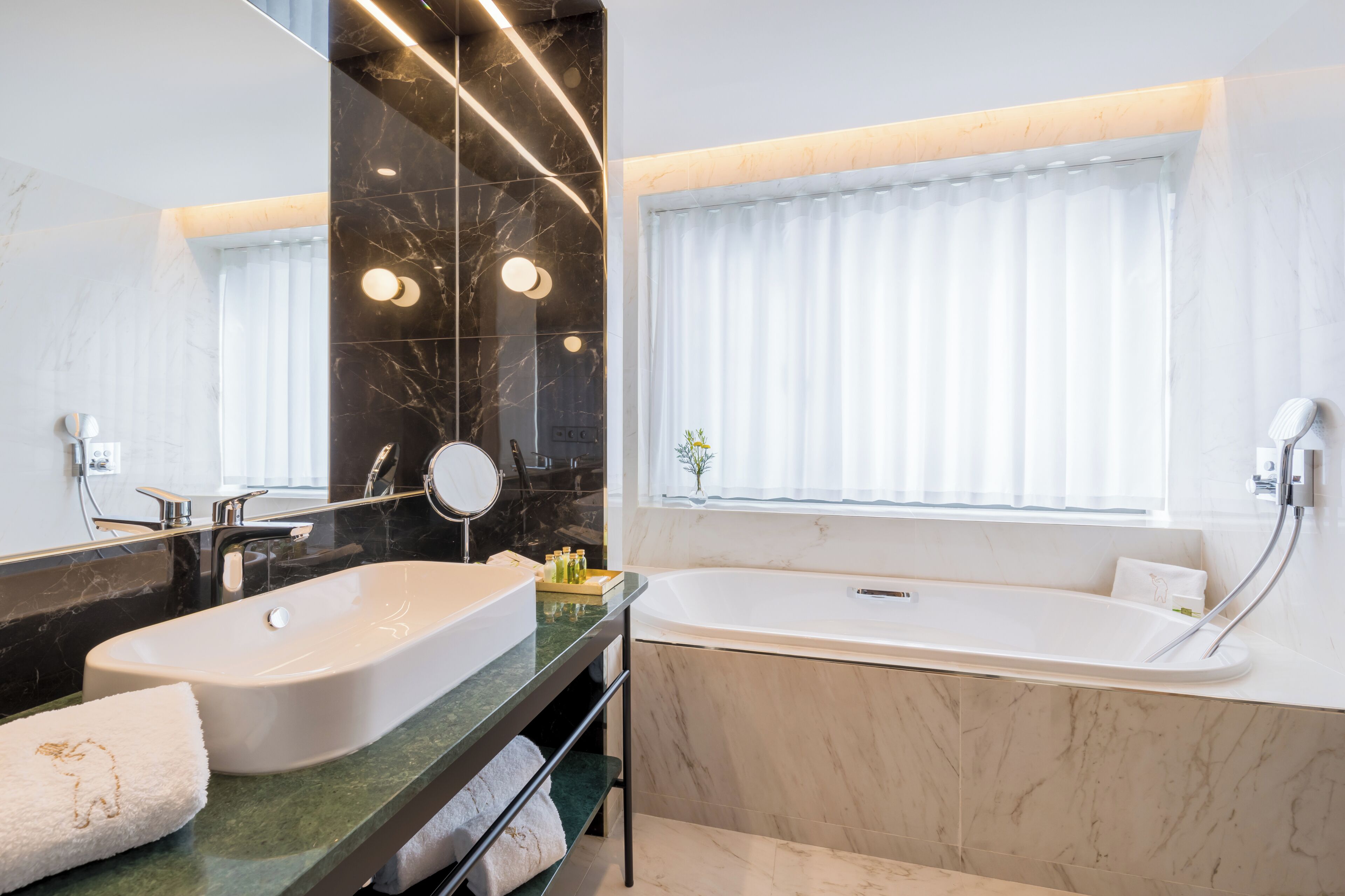 Un baño moderno con dos lavamanos, una bañera y un espejo grande.