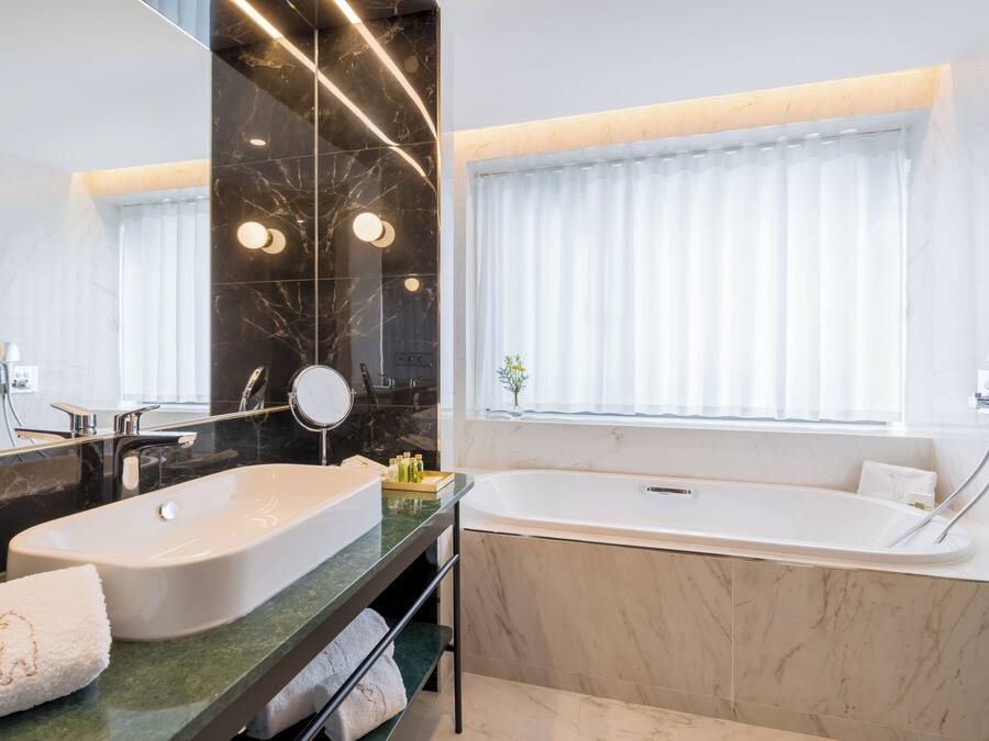 Uma casa de banho moderna com duas pias, uma banheira e um espelho grande.