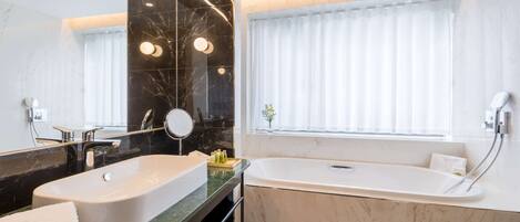 A modern bathroom with dual sinks, a large mirror, and a standalone bathtub.