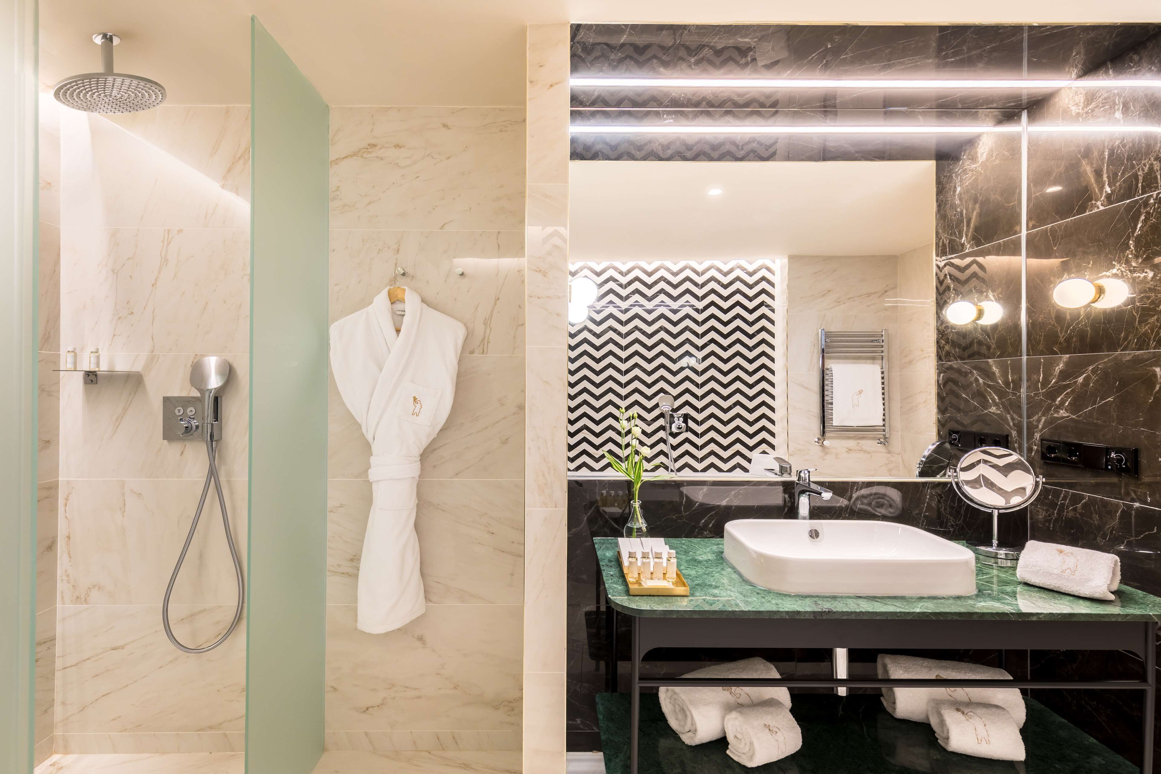 A modern bathroom with a shower, a vanity with a mirror, and a towel rack.