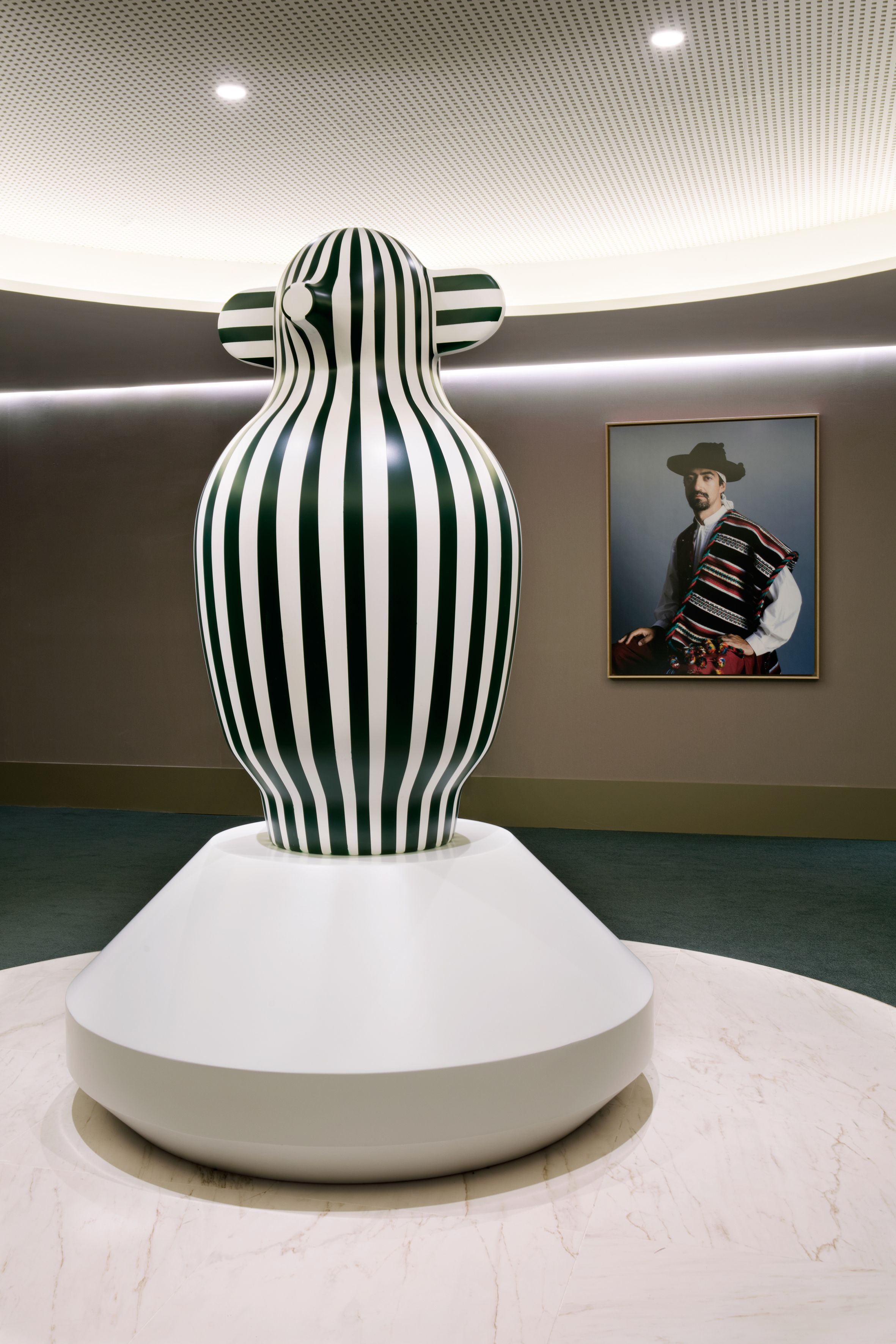 Eine moderne Skulptur mit vertikalen Streifen auf einem Sockel in einer Galerie.