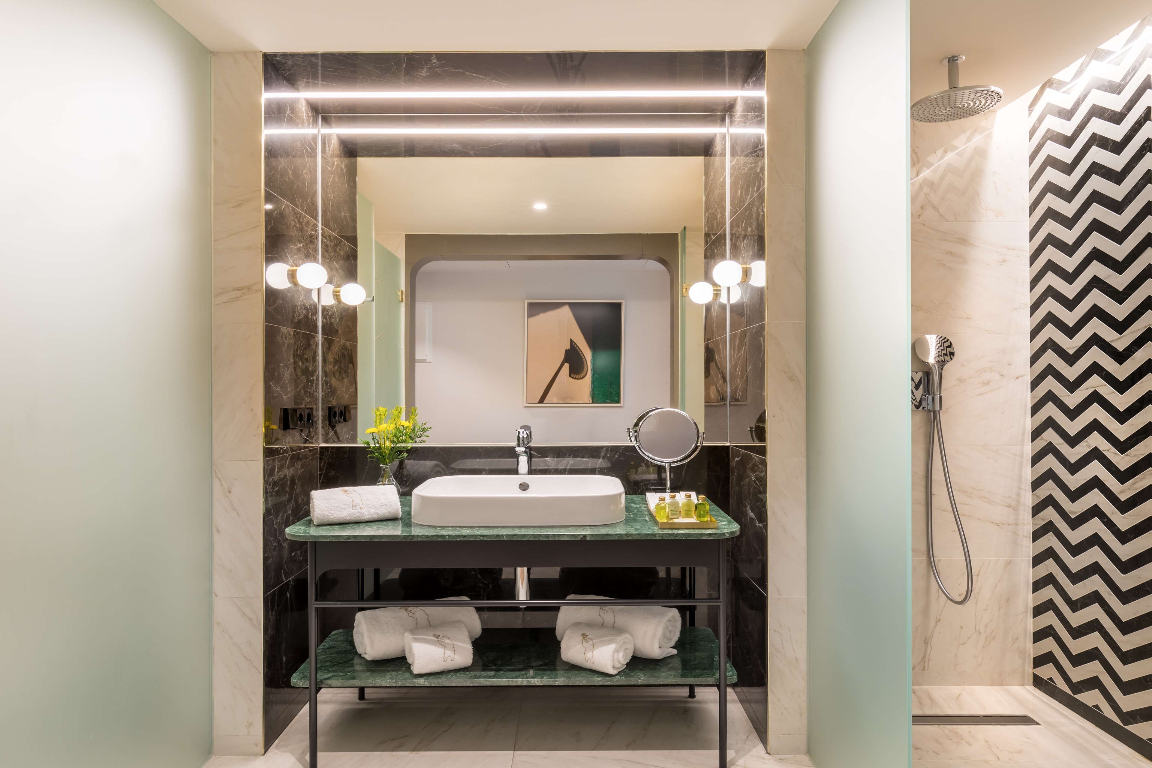 A modern bathroom with a large mirror, a sink, and a shower.