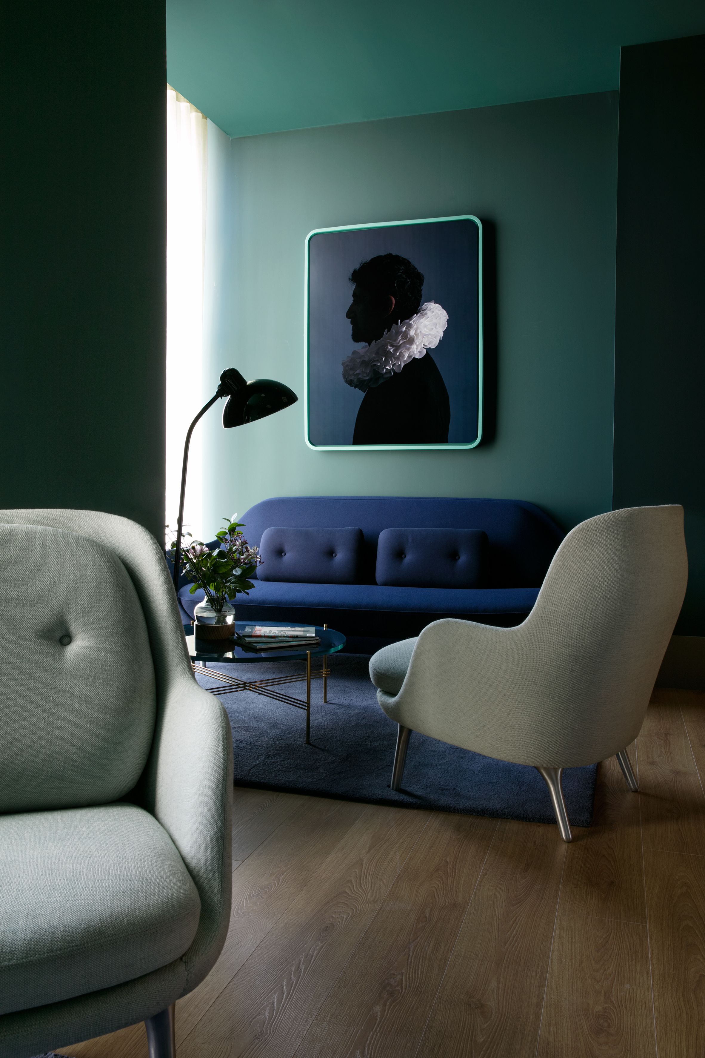 Una sala de estar moderna con un sofá azul, un sillón blanco y una lámpara de pie.