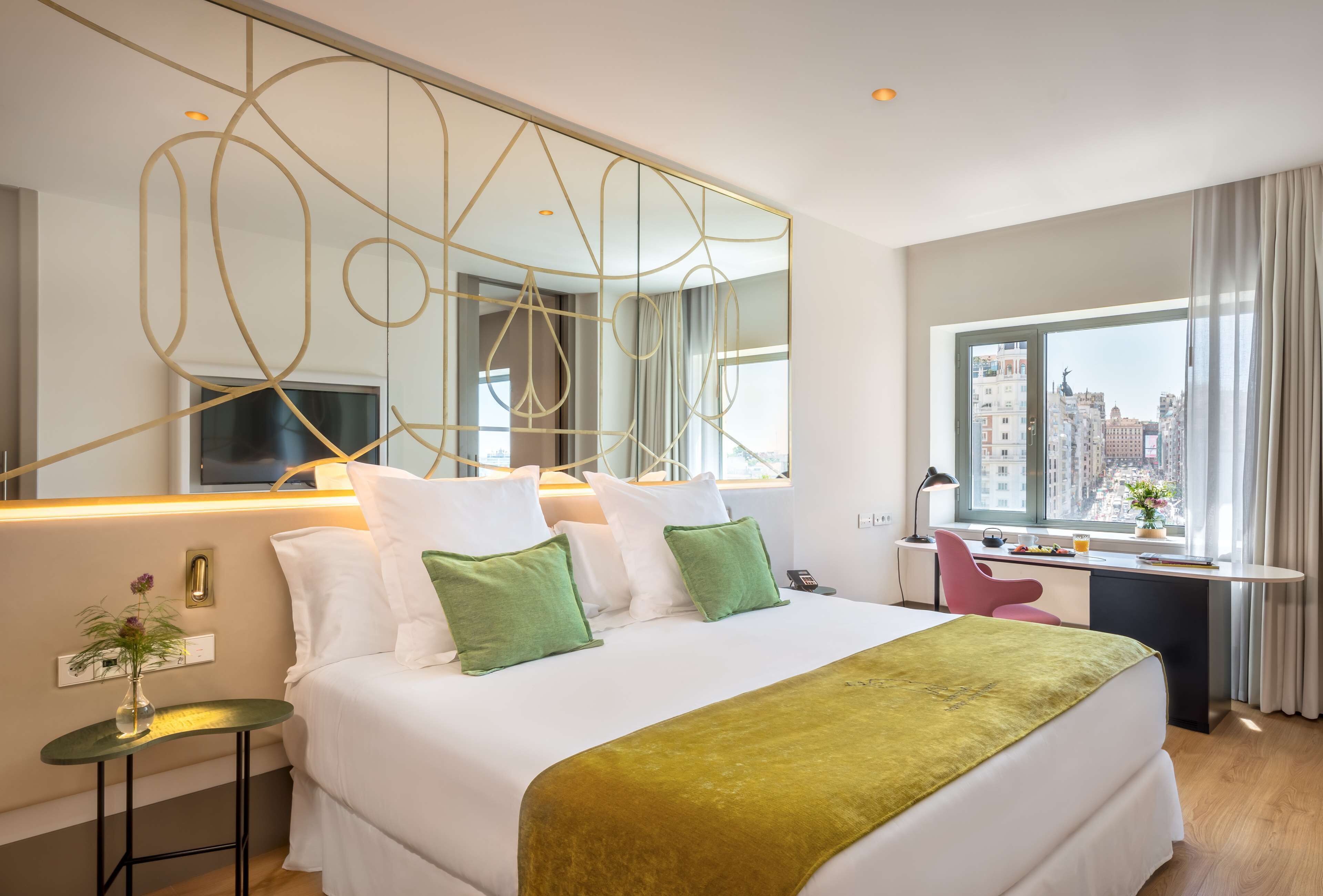 Ein modernes Hotelzimmer mit einem großen Bett, einem Schreibtisch und Blick auf die Stadt.