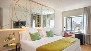 Una habitación de hotel moderna con una cama grande, un escritorio y vistas a la ciudad.