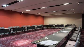 Un salón de conferencias con una larga mesa, varias sillas y una alfombra roja.