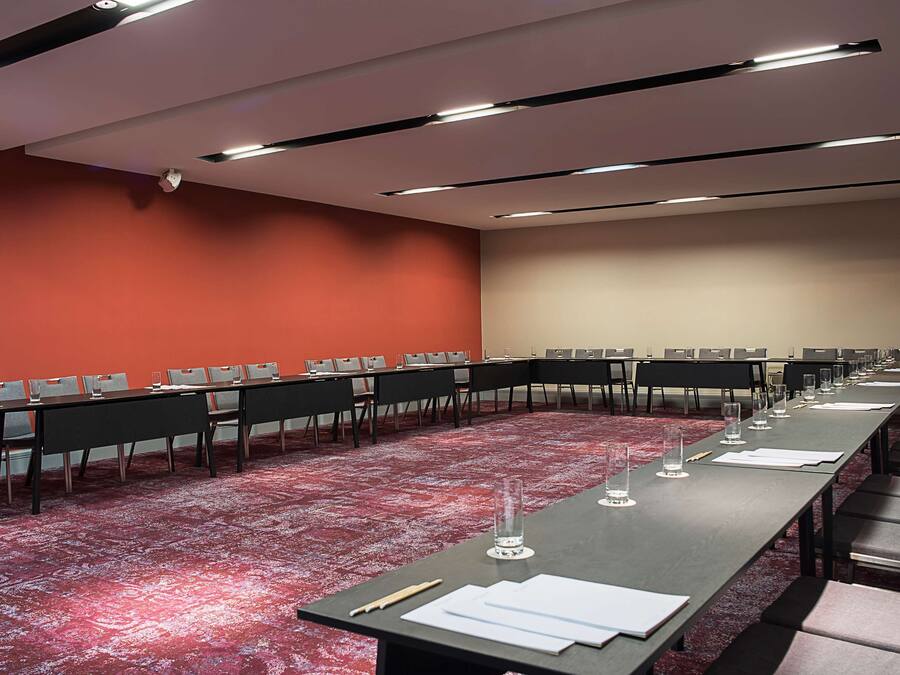 Un salón de conferencias con una larga mesa, varias sillas y una alfombra roja.