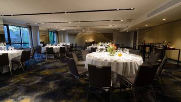 Un salón de conferencias con varias mesas redondas dispuestas para comedor, equipado con sillas y vajilla.