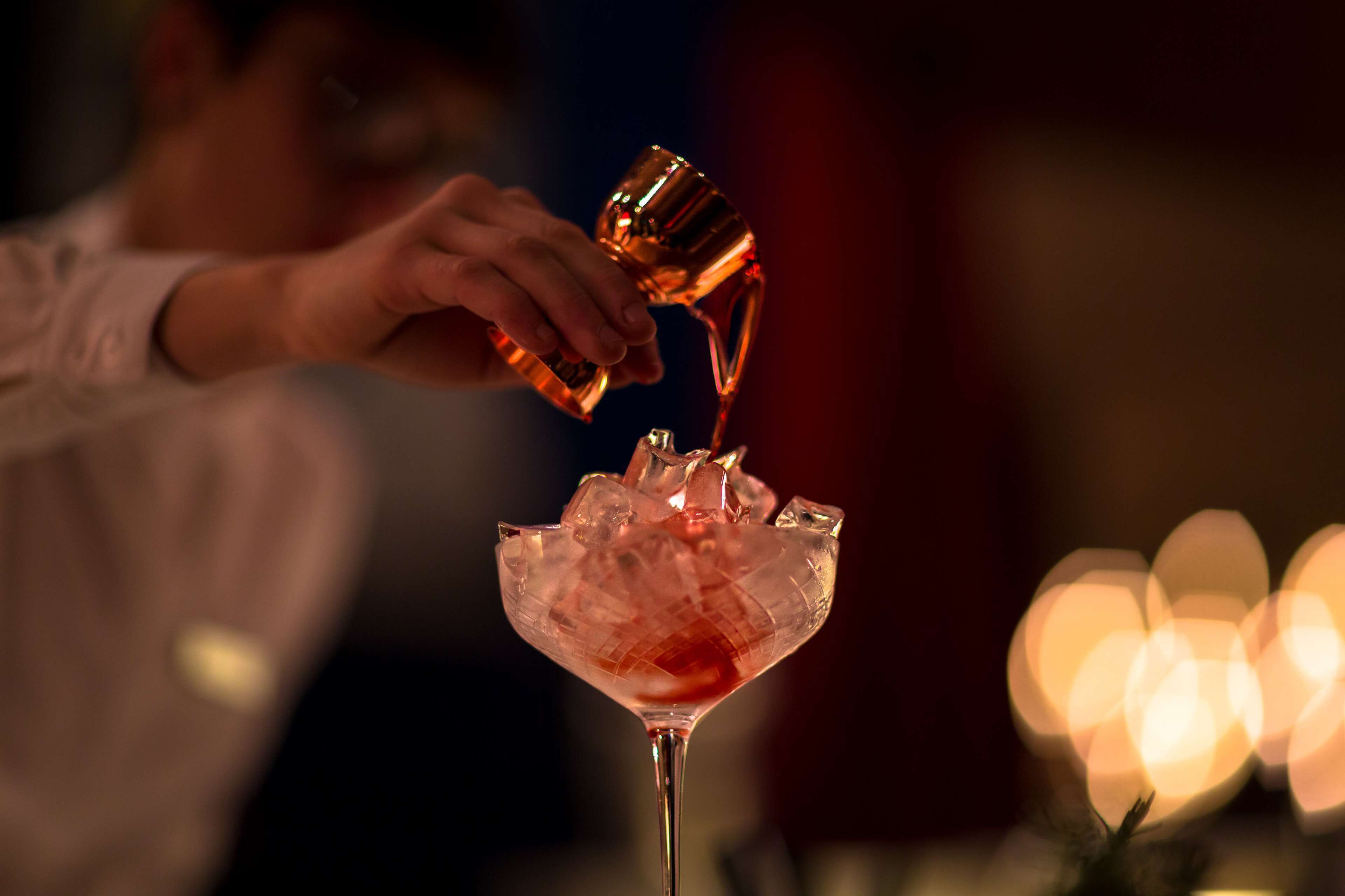 Una persona sirviendo una bebida en un vaso con hielo.