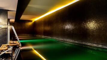 A modern indoor pool with a reflective floor and a long, narrow pool area.
