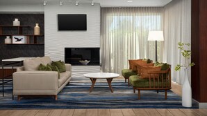 A modern living room with a sofa, armchair, coffee table, and a flat-screen TV mounted on the wall. - Fairfield Inn & Suites by Marriott Panama City Beach (Panama City Beach)