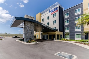 A Fairfield Inn & Suites by Marriott hotel with a modern entrance, stone pillar, and a parking lot.