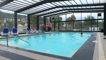 Una piscina cubierta, una piscina al aire libre, sombrillas, tumbonas