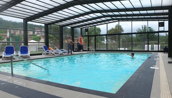 Alberca techada, alberca al aire libre y sombrillas en la alberca