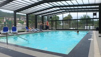 Una piscina techada, una piscina al aire libre, sombrillas