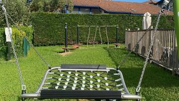 A playground with a swing set and a netted play area.