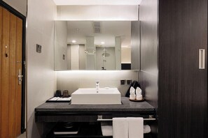Un baño moderno con un espejo grande, un lavamanos y una ducha.