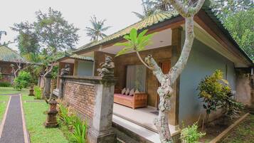 A traditional house with a tiled roof, a porch with a bench, and a stone statue.