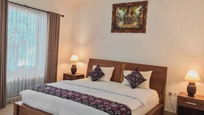 Una cama bien tendida con una colcha floral, dos lámparas de noche y un cuadro en la pared.