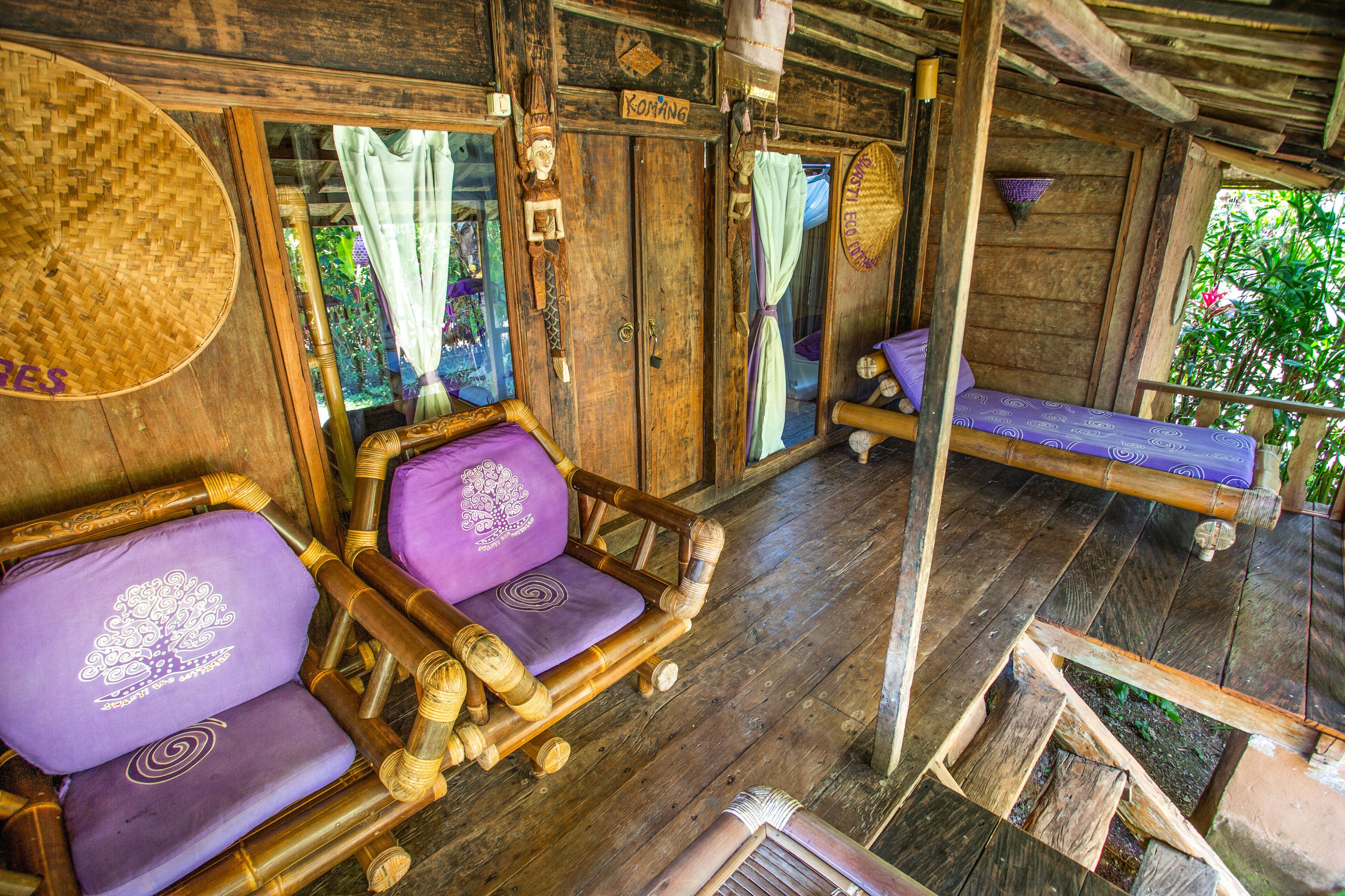 Una habitación de madera con una cama, dos sillas y un banco.