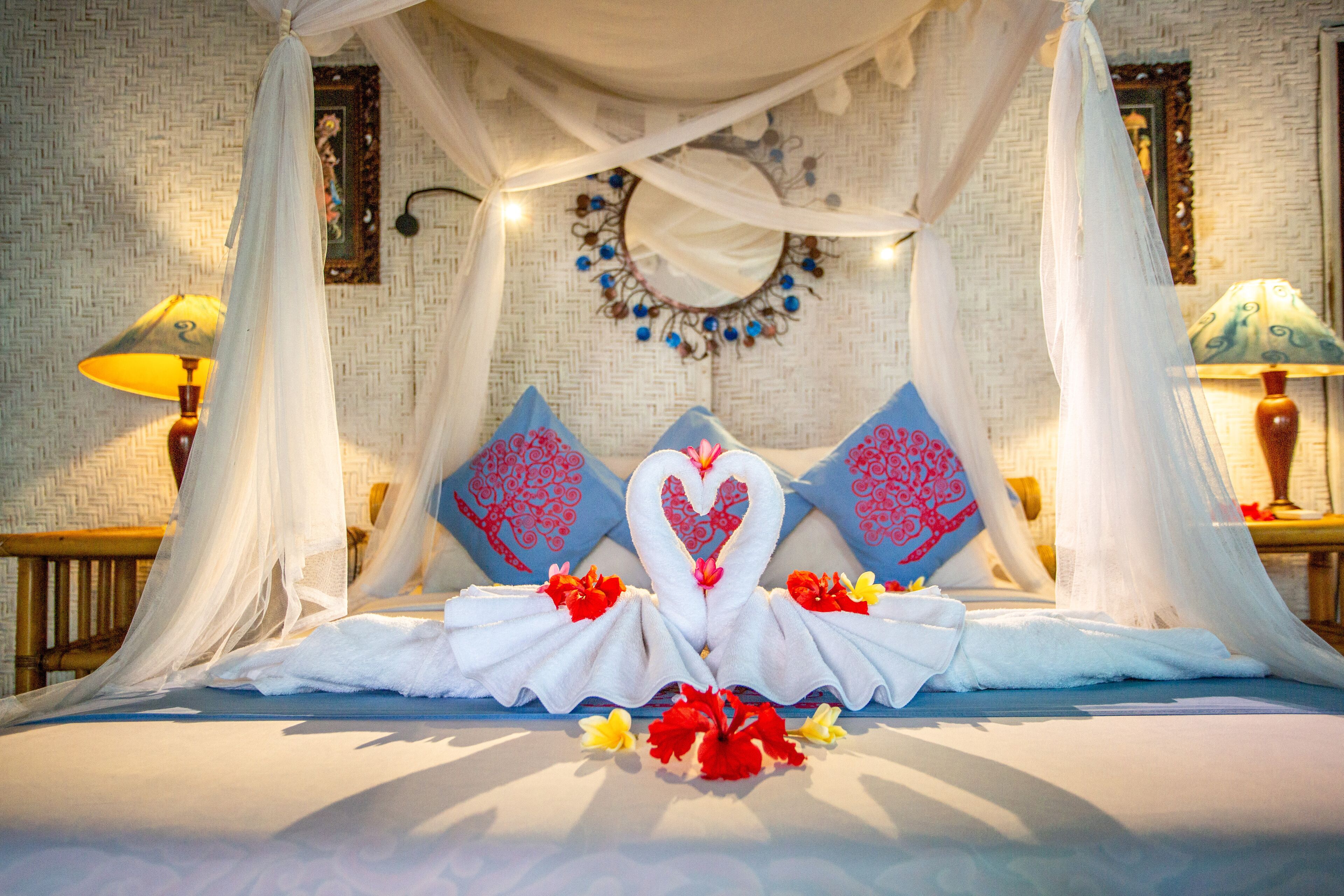 Un lit à baldaquin, agrémenté de coussins décoratifs et de compositions florales.