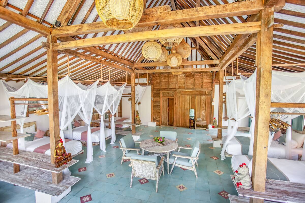 A traditional wooden structure with multiple beds, each with a canopy, and a central round table with chairs.