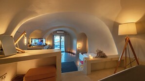 Een moderne hotelkamer met een gebogen plafond, een bureau met computer, een bed en uitzicht op de stad door een groot raam.