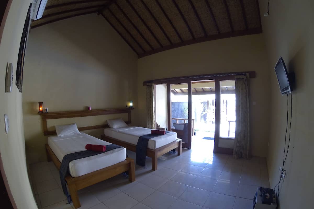 Quarto com duas camas, televisão e vista para o exterior.