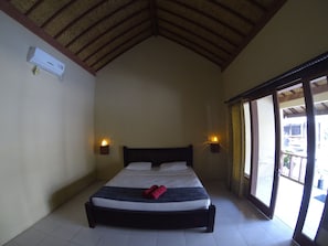 A bedroom with a bed, two wall-mounted lights, a ceiling fan, and a window with a view of the outside.