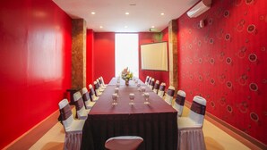 A conference room with a long table, chairs, and a projector screen. - Grand Inn Hotel Mataram (Mataram)