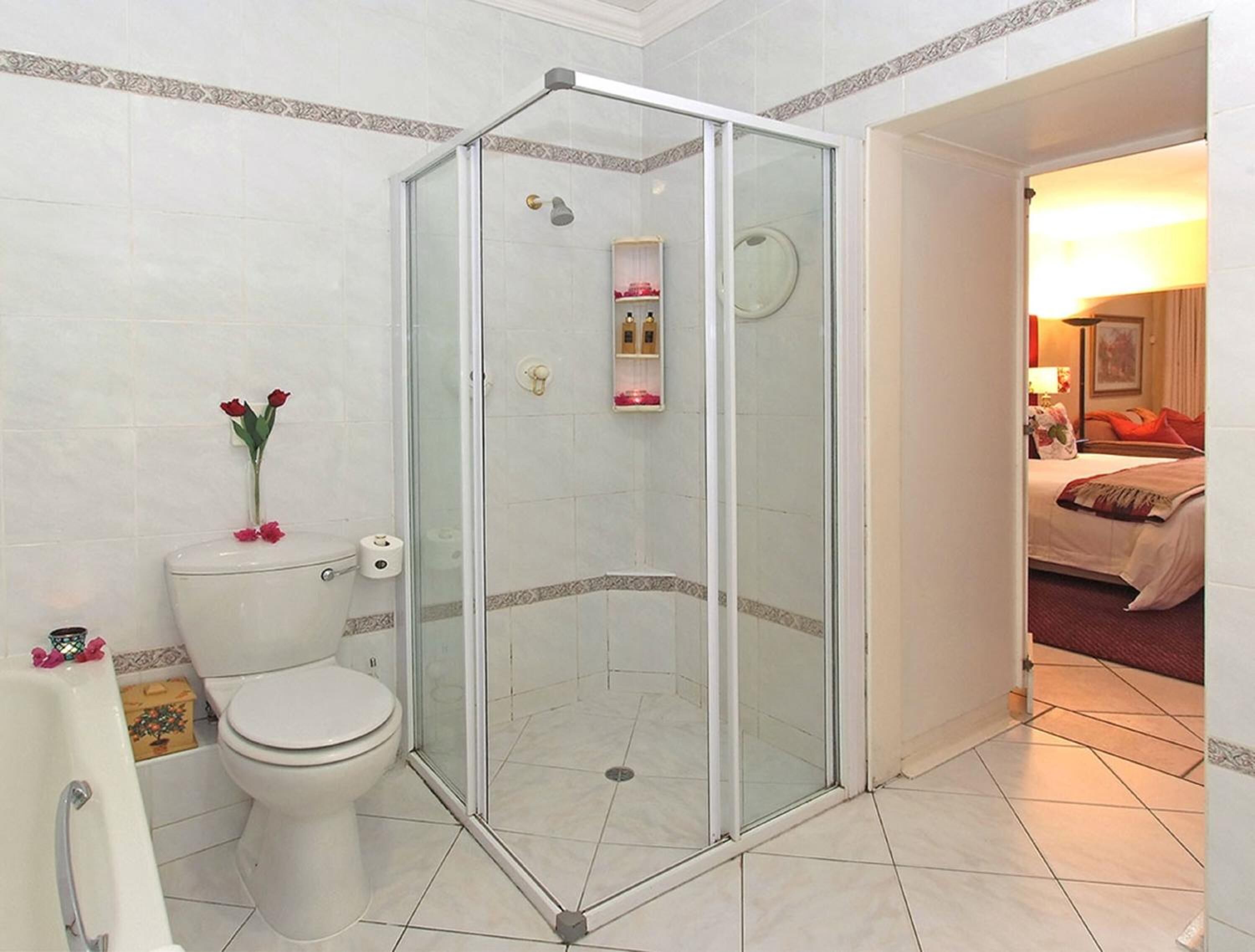 A hotel bathroom with a glass-enclosed shower, a toilet, and a sink.