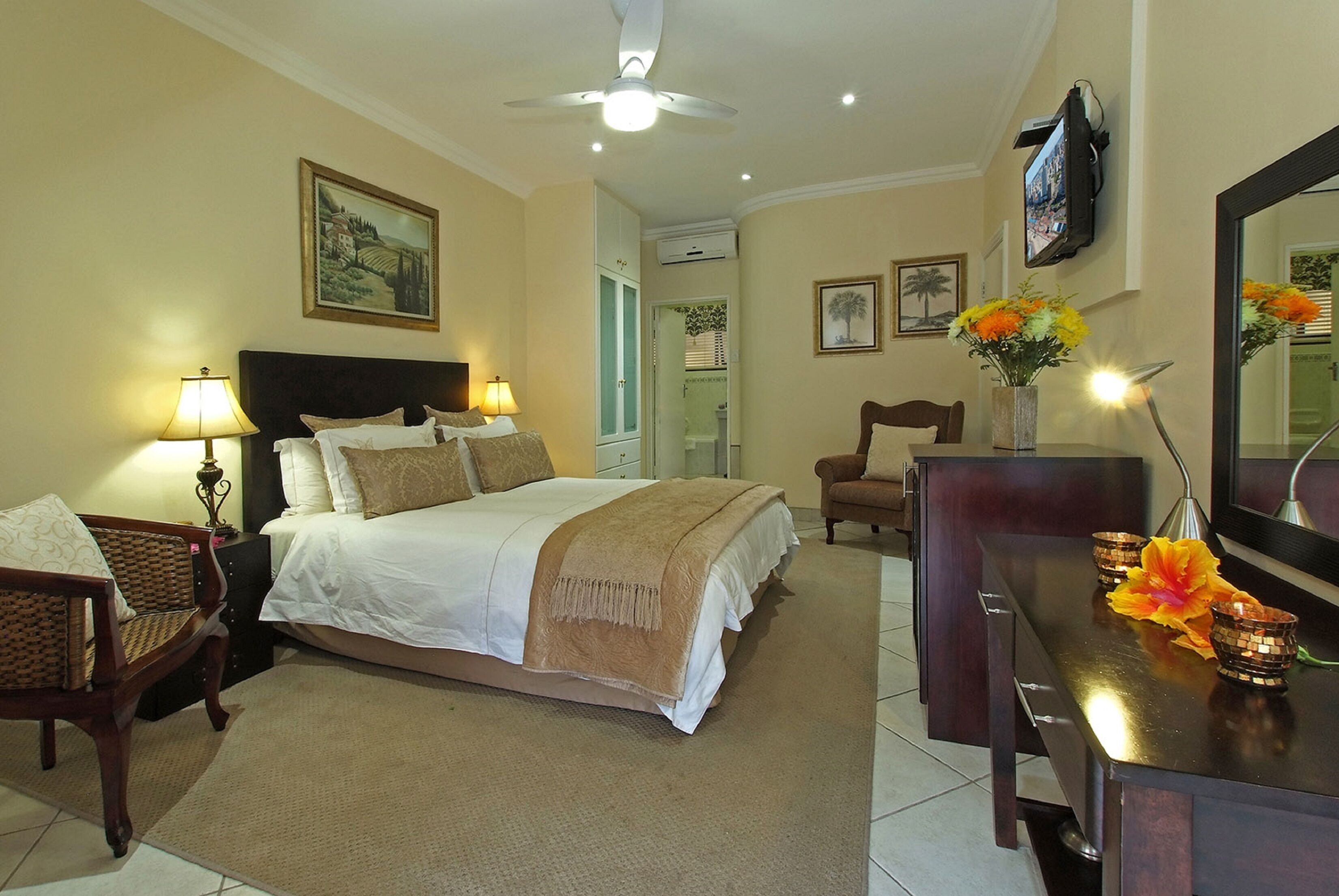 A hotel room with a bed, a desk, a chair, a TV, and a ceiling fan.