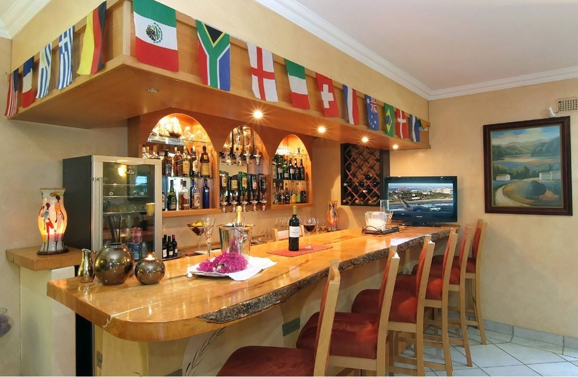 A bar area with multiple flags, a television, and a wine bottle on the counter.