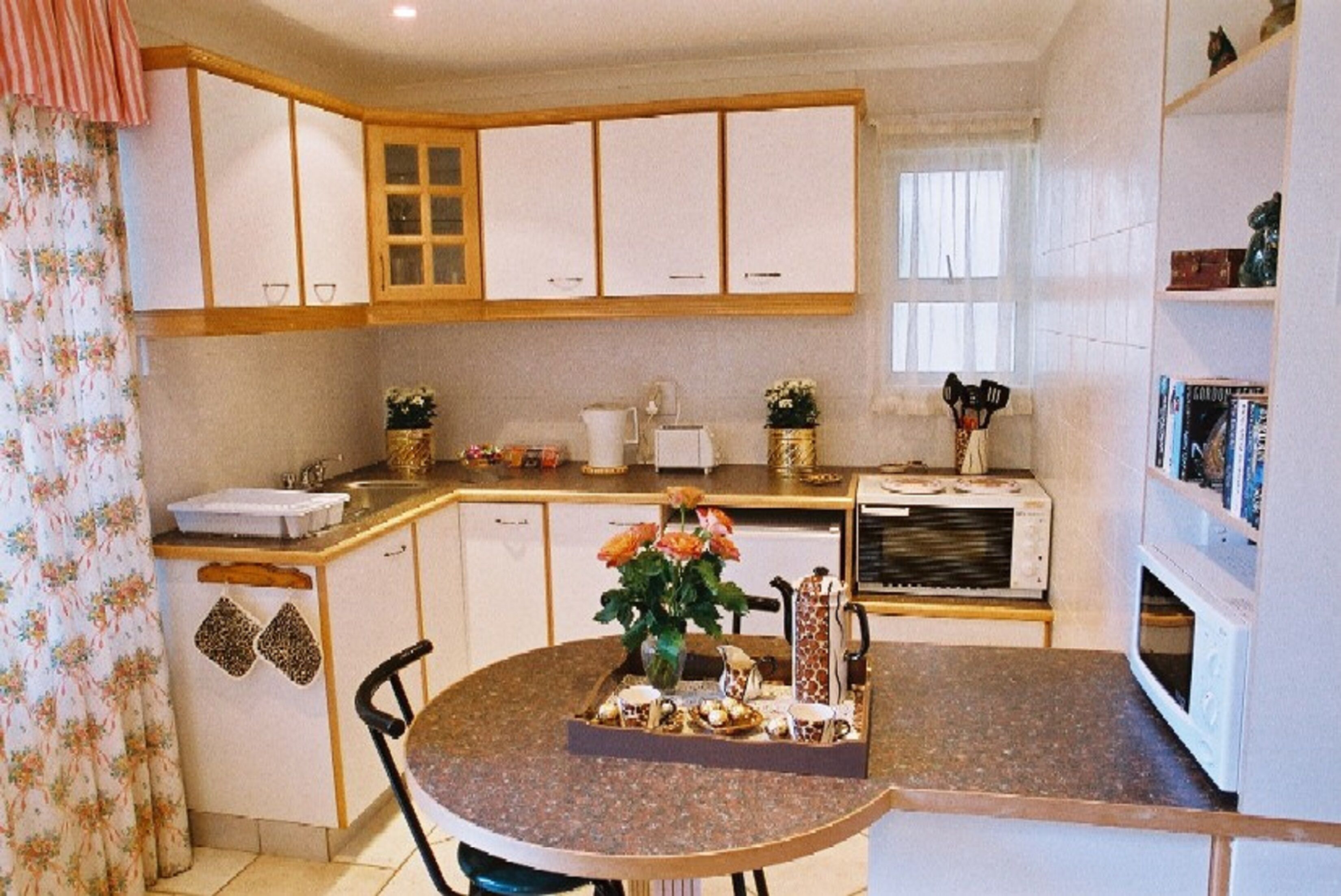 A compact kitchen with white cabinets, a granite countertop, and a dining area with a table and chairs.