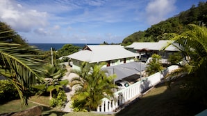 A coastal resort with multiple buildings, lush greenery, and a view of the ocean.