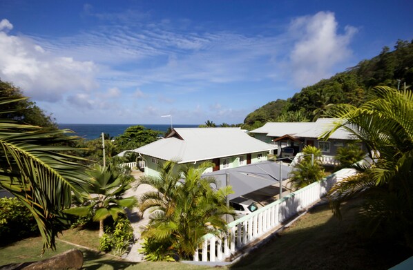 A coastal resort with multiple buildings, lush greenery, and a view of the ocean.