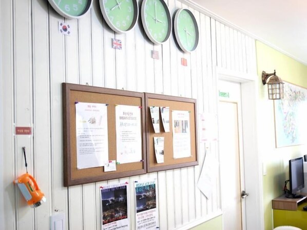 A bulletin board with notices, a clock, and a wall-mounted lamp.